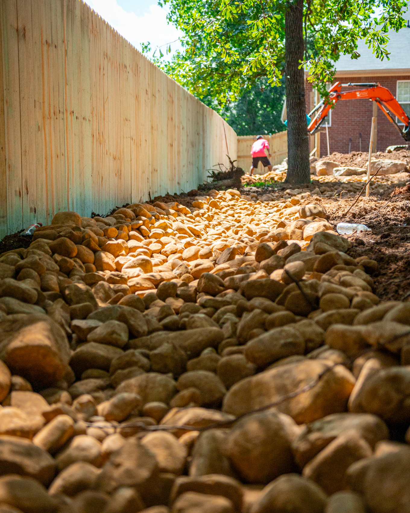 Dry creek bed of river rock running along a fence line