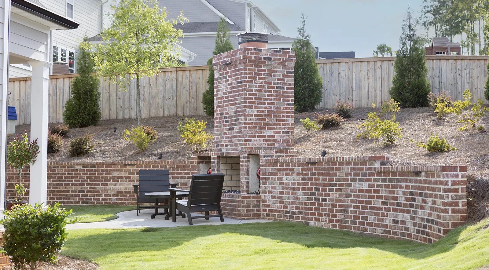 Brick outdoor fireplace and seat wall around a patio with a table and chairs